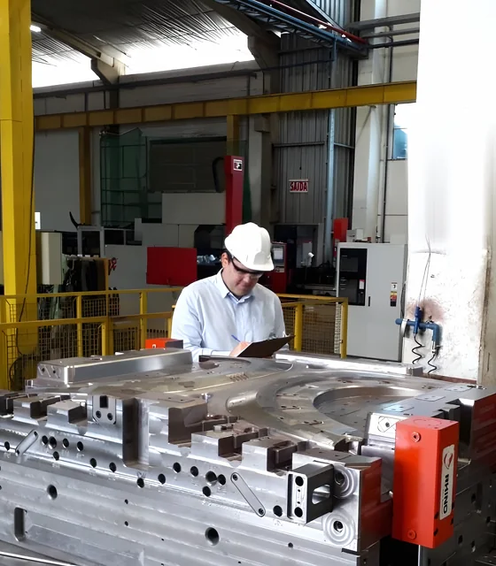 Rafael Beck, de capacete e prancheta, examina um molde de grande porte em chão de fábrica durante vistoria técnica